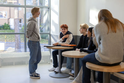Teenagers sitting and talking on school corridor