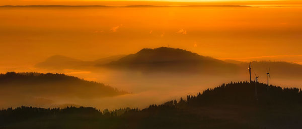 Scenic view of silhouette mountains against orange sky