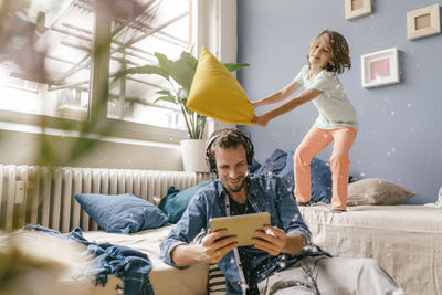 Young woman using mobile phone while sitting on bed