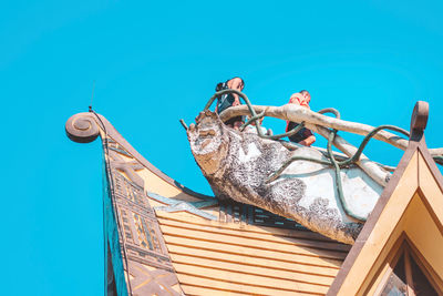 Low angle view of woman sitting against blue sky