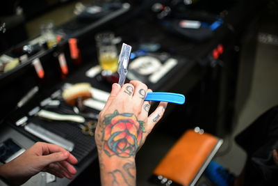 Close-up of tattooed hand of a barber holding straight razor