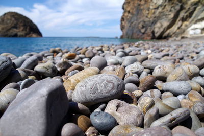 Close-up of pebbles on beach against sky