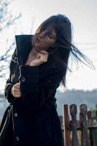 Close-up of young woman standing against sky