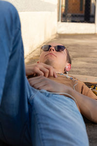 Vertical view of teenager on sunglasses lying down listening to music looking at the sky view