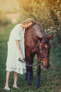 Woman leaning on horse in grass