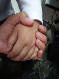 Close-up of father holding baby hand