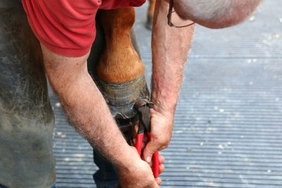 Low section of man holding hands standing on wood