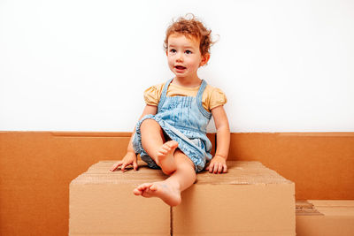 Full length of cute baby girl sitting in box