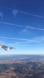 Airplane wing over clouds against blue sky