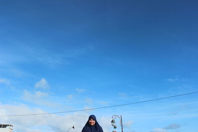 Low angle view of woman against blue sky