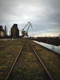 Railroad track by river with crane in background