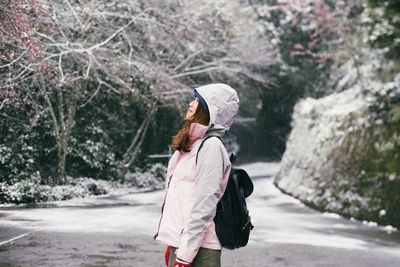 Young woman in warm clothing standing on snow covered road