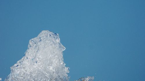 Close-up of frozen ice against clear blue sky