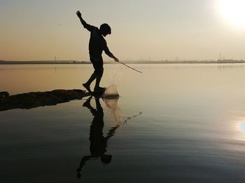 Full length of silhouette man fishing in lake against sky during sunset
