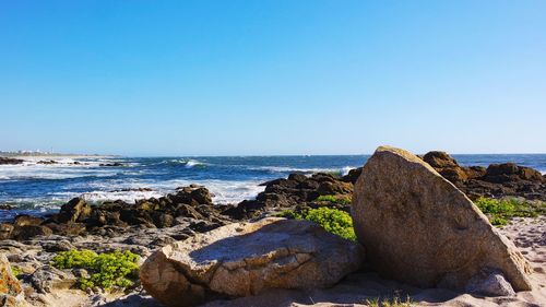 Rocks on beach against clear sky