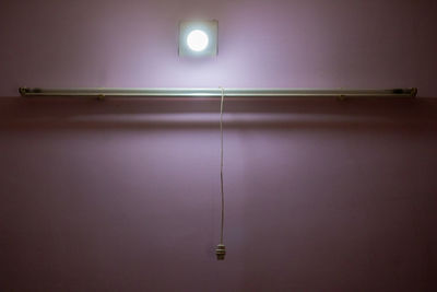 Illuminated light bulb on wall at home