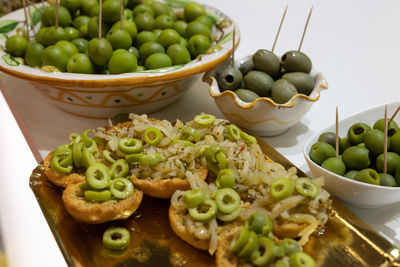 Appetizer of small pieces of toasted bread with olives and oregano.