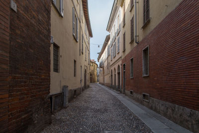 Narrow alley amidst buildings empty street in august morning 