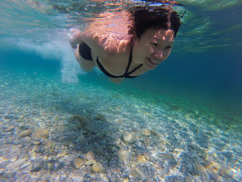 Smiling woman swimming underwater