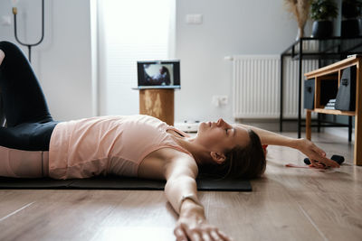 Woman in sports clothes does fitness cardio exercises at home, using laptop