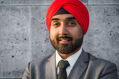 Close-up portrait of businessman wearing turban standing against wall