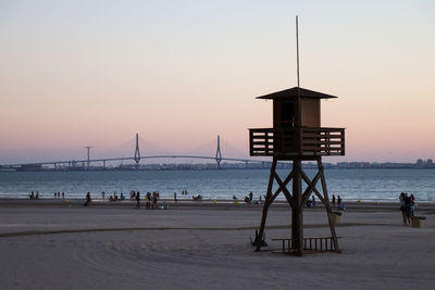 Lifeguard hut on beach against clear sky during sunset