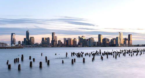 Sea and buildings in city against sky