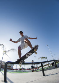 Full length of man skateboarding on skateboard against clear sky