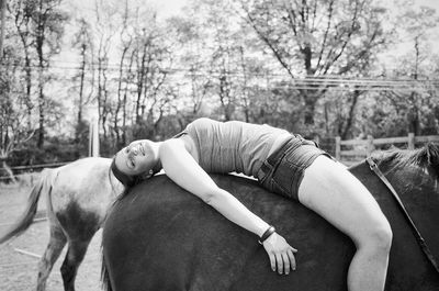 Side view of smiling woman lying on horse