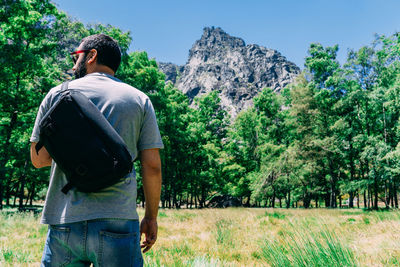 Rear view of man standing on field against mountain