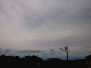 Low angle view of silhouette electricity pylons against sky at sunset