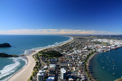 High angle view of sea and buildings against blue sky