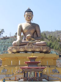 Statue against temple against clear sky