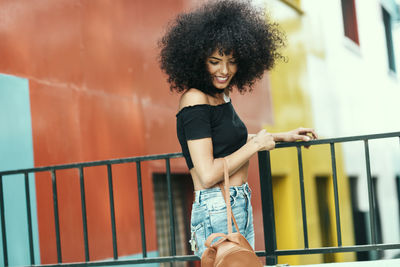 Smiling woman with curly hair standing by railing