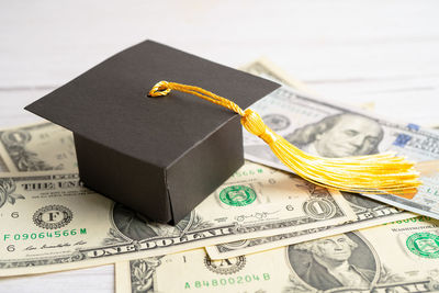 Close-up of mortarboard on paper currency against white background