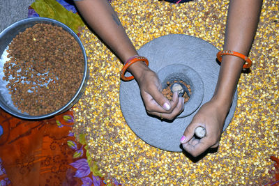 A village woman's hand, grinds gram in an old hand operated flour mill.