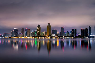 Illuminated city by buildings against sky