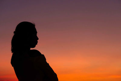 Silhouette woman standing against orange sky