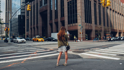 Rear view of female standing on sidewalk