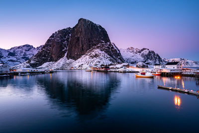 Scenic view of lake by snowcapped mountains against clear sky during winter