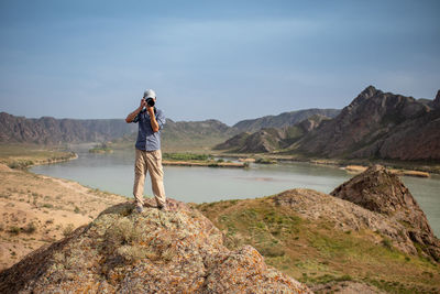 Rear view of man standing on mountain against sky