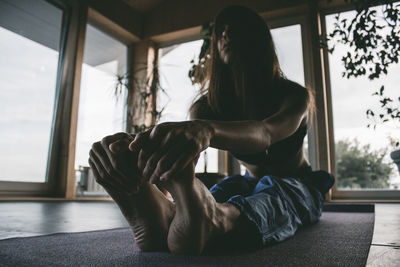  woman stretching while sitting on floor at home