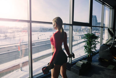 Rear view of woman looking through window