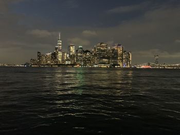 Sea by modern buildings in city against sky