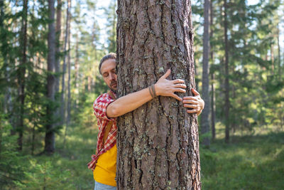 Man hands hugging large tree in park. people feel energy of nature, forest through embrace of trees