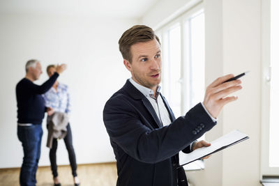 Real estate agent examining house with couple discussing in background