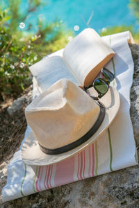 High angle view of hat with book and sunglasses on fabric