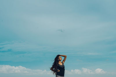 Young woman against blue sky