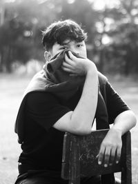 Young man looking away while sitting outdoors