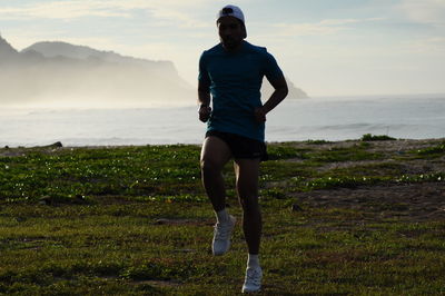 Man jogging by sea against sky